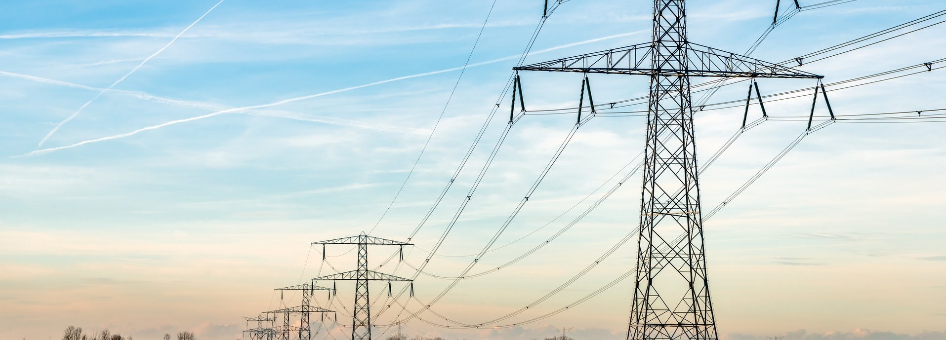 Beschreibung: Überblick über Strommasten und Hochspannungsleitungen in einer langen Reihe in einer ländlichen Landschaft in De Biesbosch aufgenommen, einem Naturgebiet in den Niederlanden