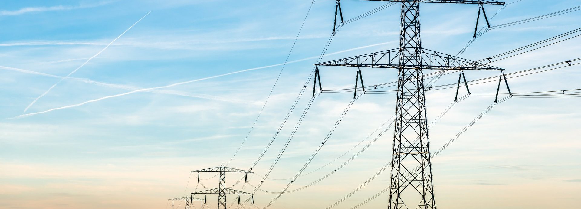 Beschreibung: Überblick über Strommasten und Hochspannungsleitungen in einer langen Reihe in einer ländlichen Landschaft in De Biesbosch aufgenommen, einem Naturgebiet in den Niederlanden