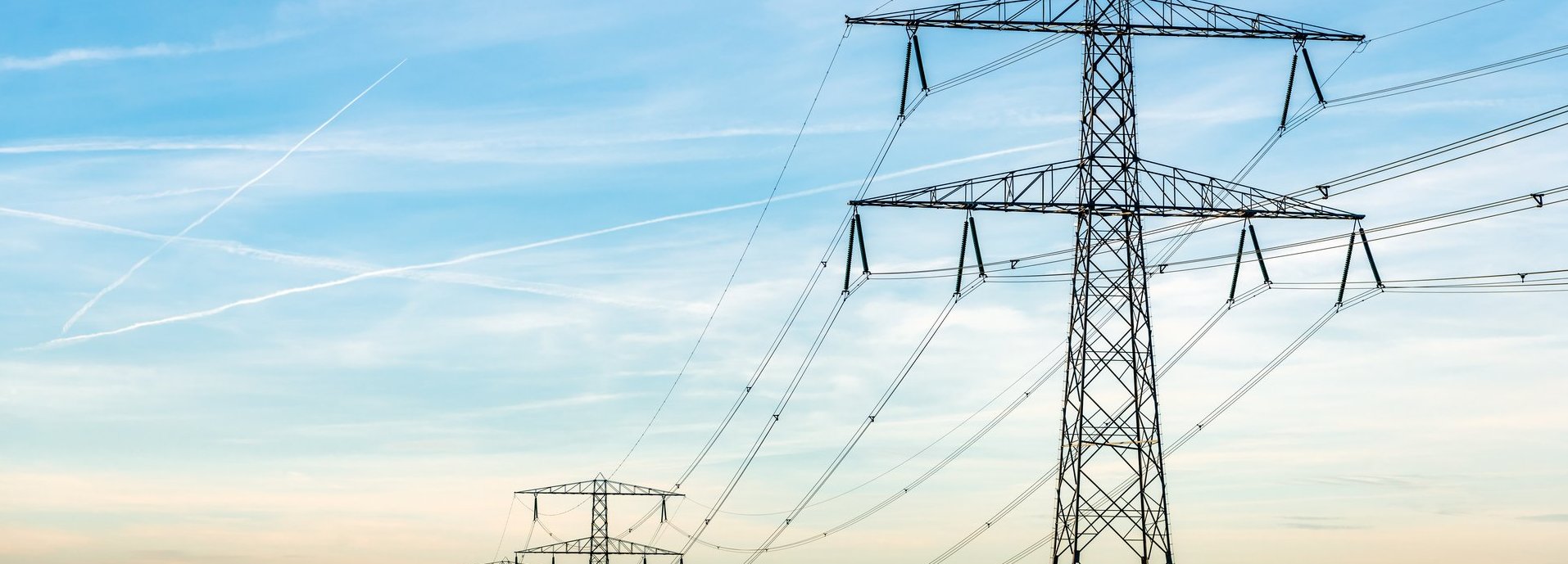 Beschreibung: Überblick über Strommasten und Hochspannungsleitungen in einer langen Reihe in einer ländlichen Landschaft in De Biesbosch aufgenommen, einem Naturgebiet in den Niederlanden