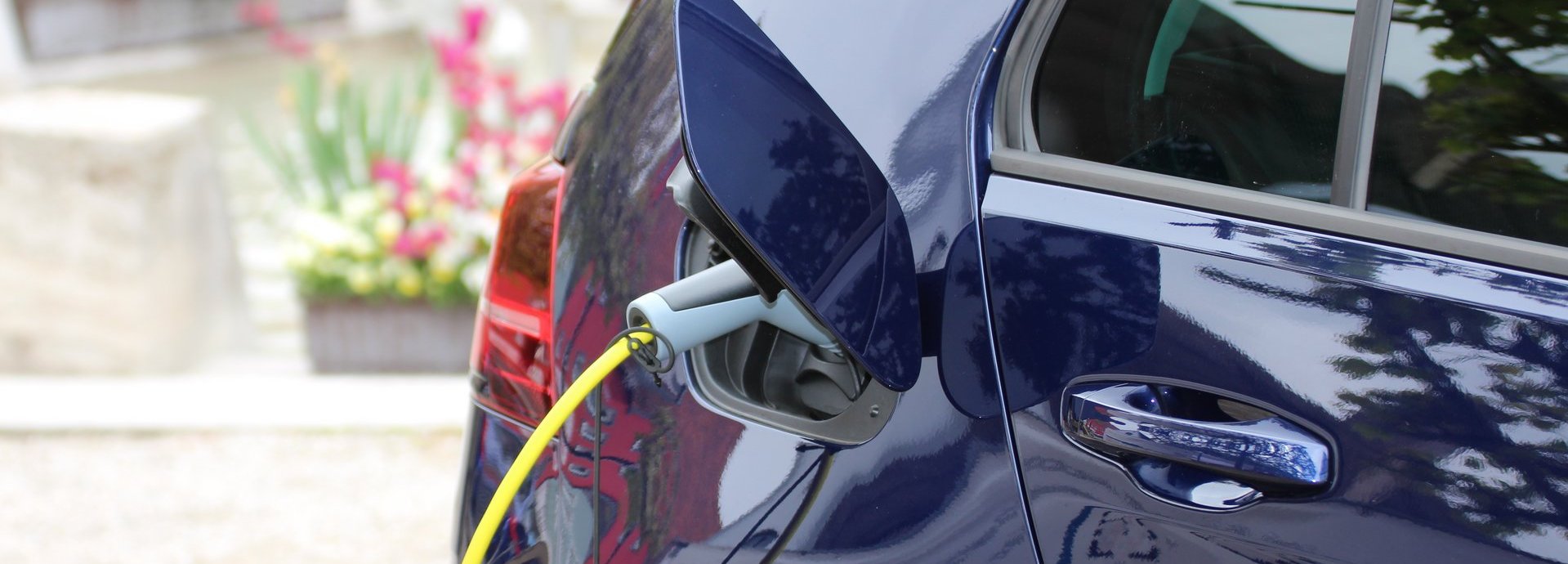 Nahaufnahme Dunkelblaues Elektroauto wird auf einem Hof geladen
