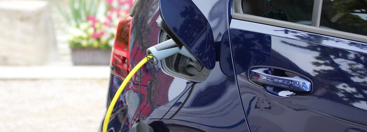 Nahaufnahme Dunkelblaues Elektroauto wird auf einem Hof geladen