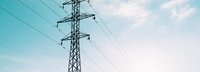 Tiefe Ansicht auf Strommast vor hellblauem leicht bewölktem Himmel