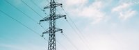 Tiefe Ansicht auf Strommast vor hellblauem leicht bewölktem Himmel