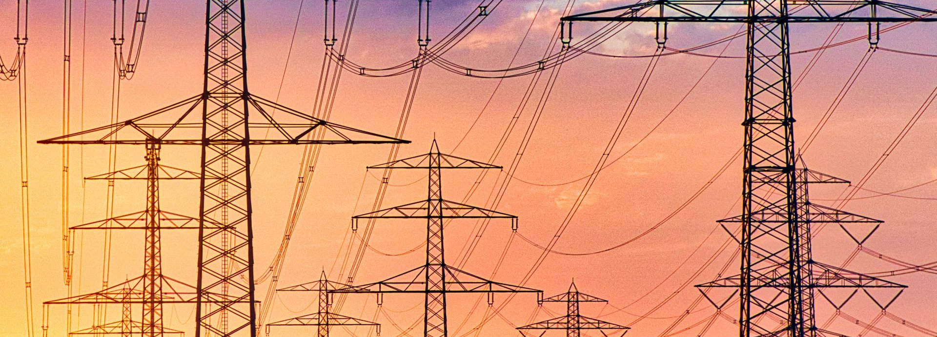 Beschreibung: Tiefe Ansicht auf viele Stromleiter vor einem gelb-roten Himmel bei Sonnenuntergang