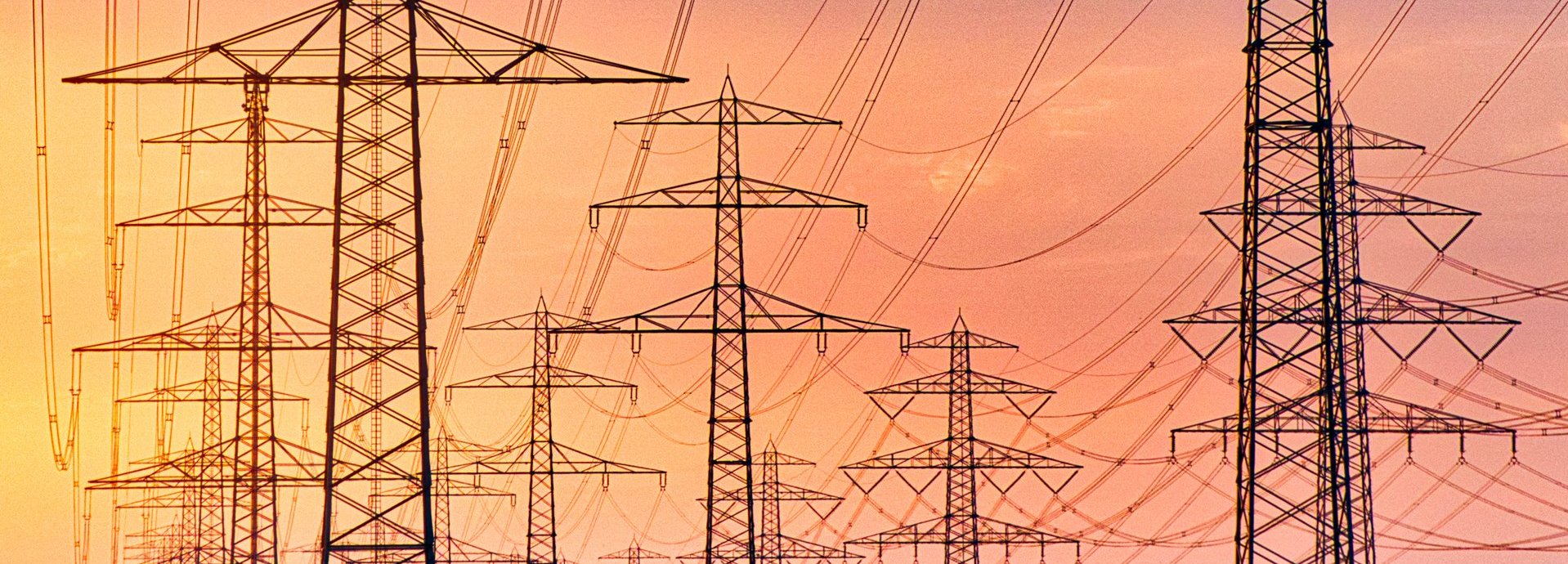 Beschreibung: Tiefe Ansicht auf viele Stromleiter vor einem gelb-roten Himmel bei Sonnenuntergang