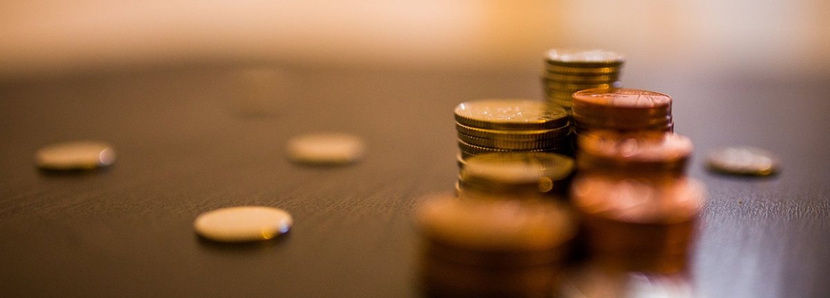 Unscharfe Aufnahme von Münzen in mehreren Stapeln auf einem braunen Tisch