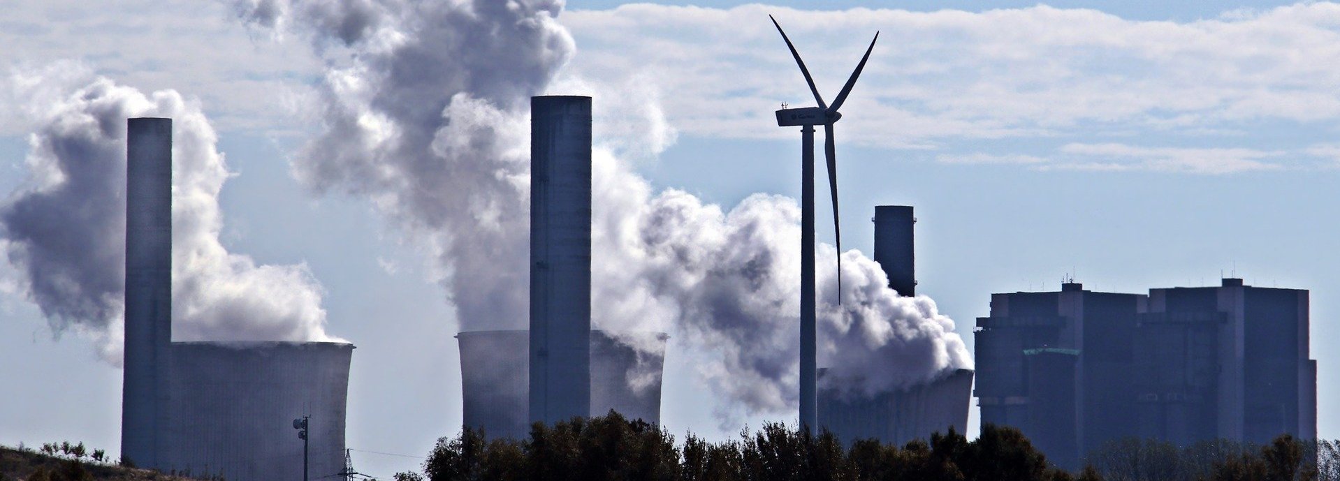 Kohlekraftwerk stößt Qualm am Horizont aus mit einem einzigen Windrad dazwischen