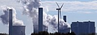 Kohlekraftwerk stößt Qualm am Horizont aus und dazwischen steht ein einziges Windrad 