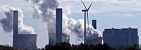 Kohlekraftwerk stößt Qualm am Horizont aus mit einem einzigen Windrad dazwischen