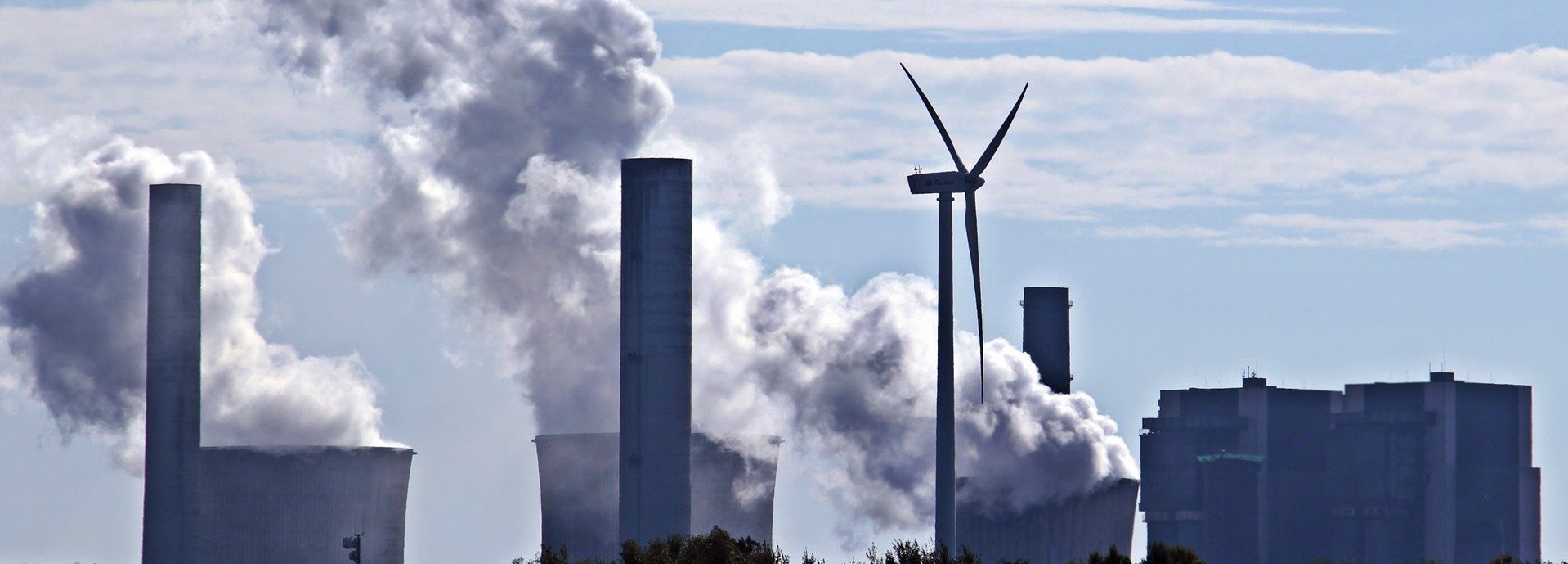 Kohlekraftwerk stößt Qualm am Horizont aus mit einem einzigen Windrad dazwischen