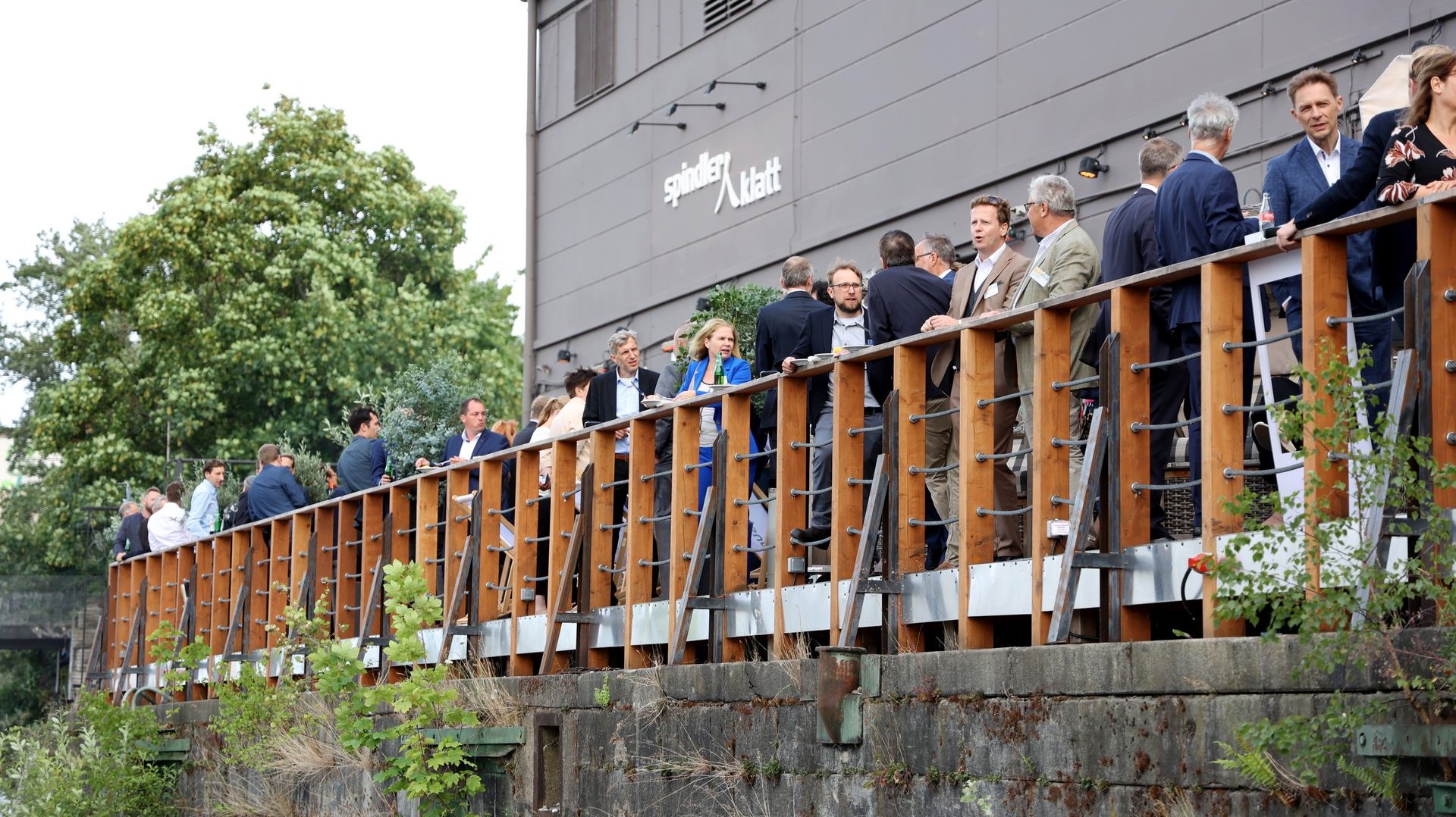 Gäste des BEE-Sommerfest stehen auf der Terrasse des Spindler&Klatt