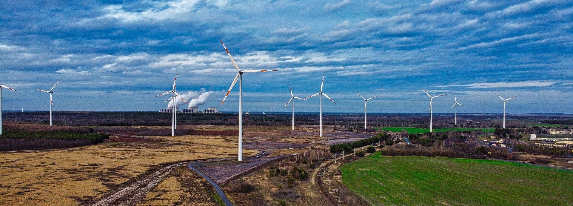 Verteilte Windräder auf Felder unter dunklen Wolken