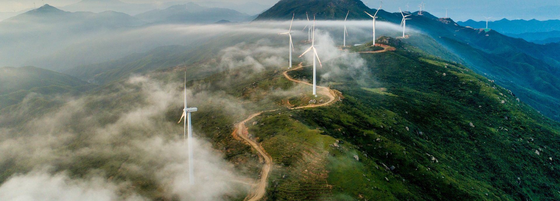 Windräder stehen an einer Straße auf einem hohen Gebirge 