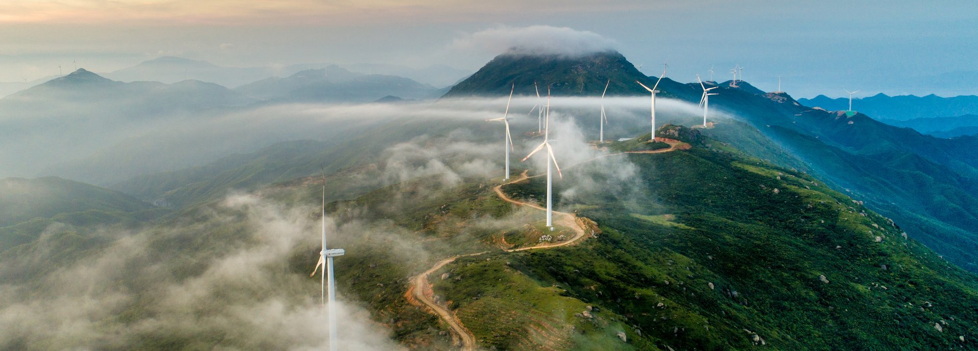 Windräder stehen an einer Straße auf einem hohen Gebirge 