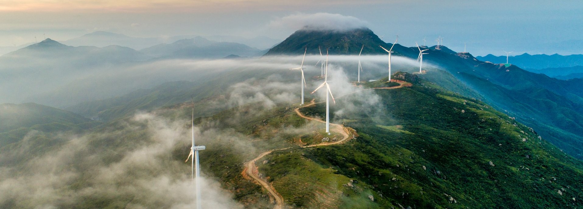 Windräder stehen an einer Straße auf einem hohen Gebirge 