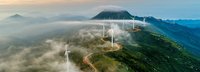 Windräder stehen an einer Straße auf einem hohen Gebirge 