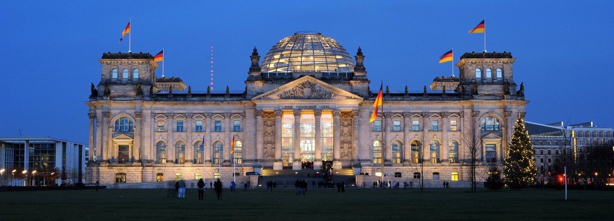 Angeleuchtetes Bundestagsgebäude vor dunkelblauem Himmel