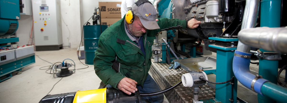 Mechaniker mit schwarzem Fass und Schlauch überprüft Biogasanlage