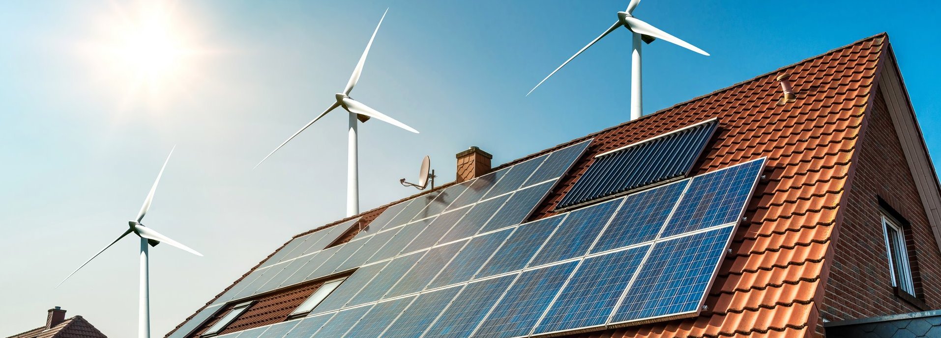 Solarkollektoren auf einem roten Dach mit Sonne und Windrädern im Hintergrund