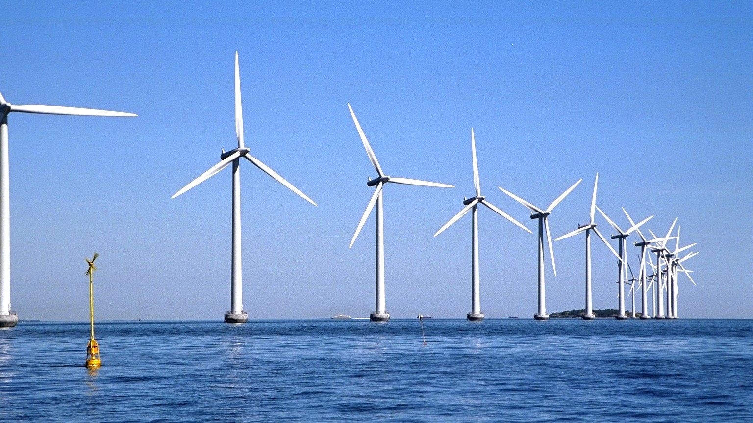 Windräder auf offener See offshore mit blauem Himmel
