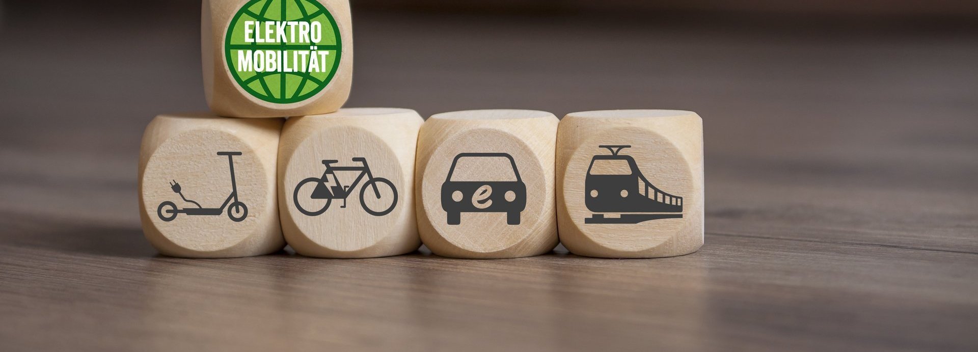 Fünf Holzwürfel mit Mobilitätssymbolen auf ainem Tisch