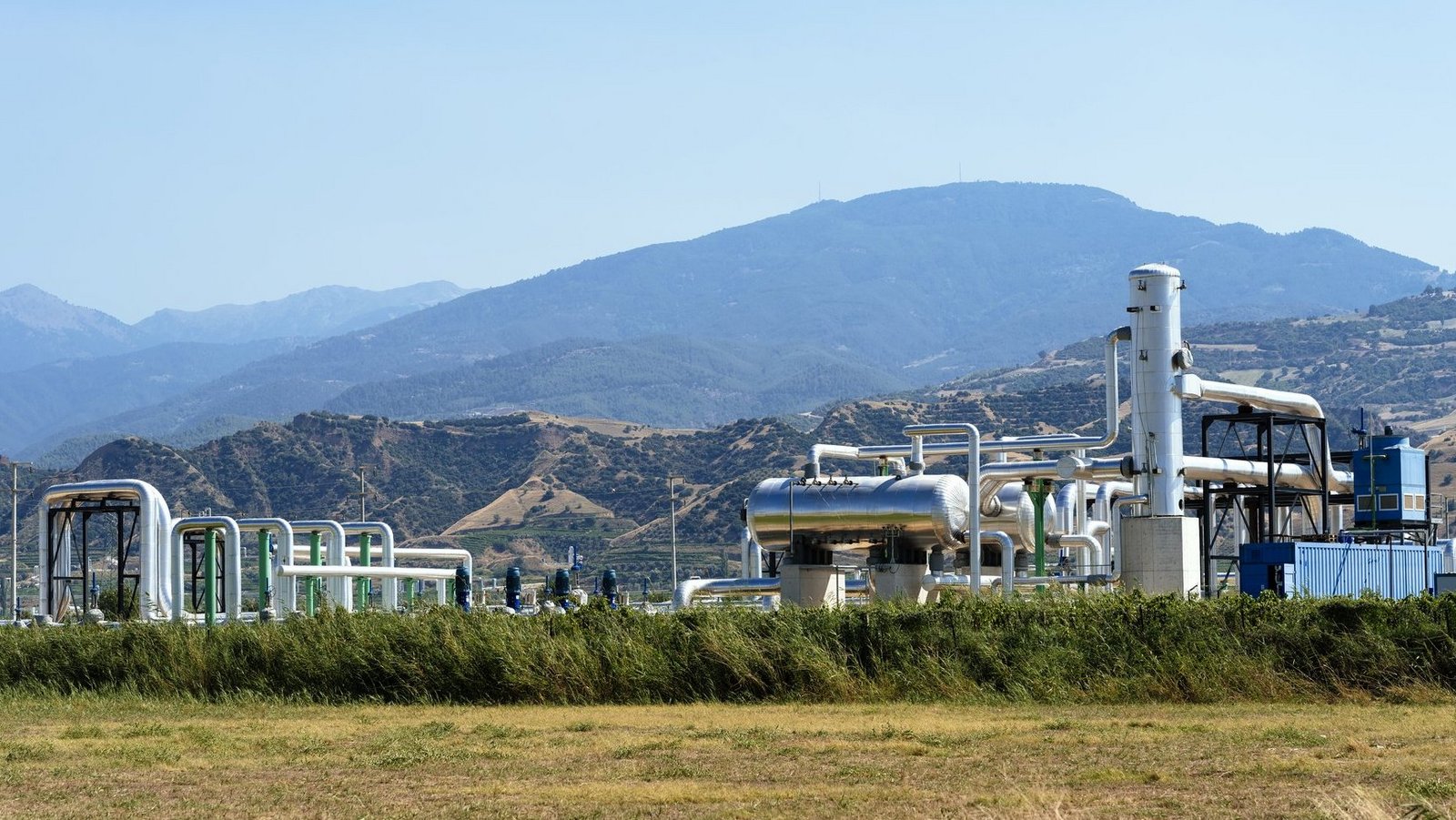 Geothermiekraftwerk vom weiten in hügeliger grüner Landschaft