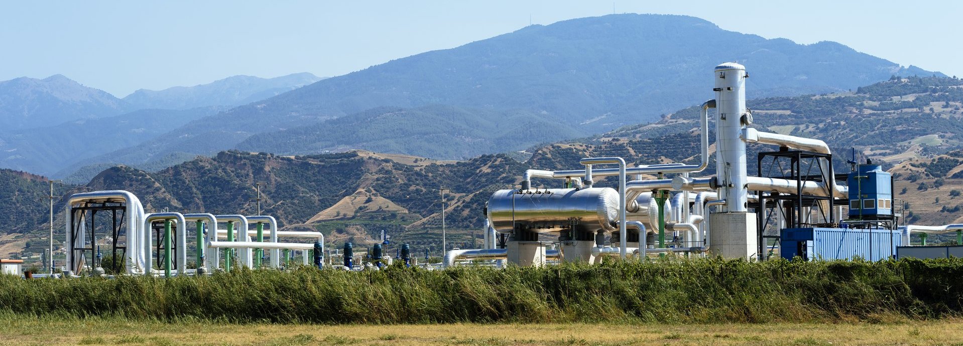 Geothermiekraftwerk vom weiten in hügeliger grüner Landschaft