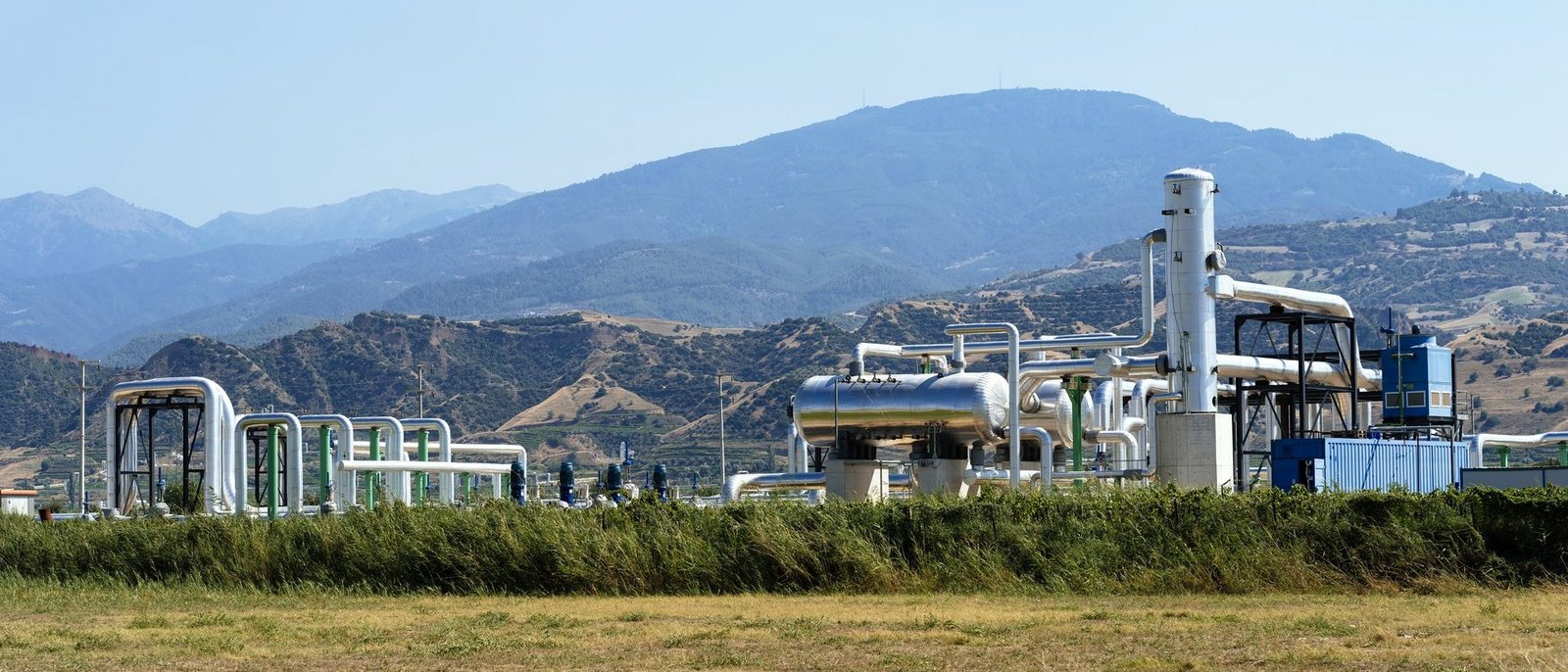 Geothermiekraftwerk vom weiten in hügeliger grüner Landschaft