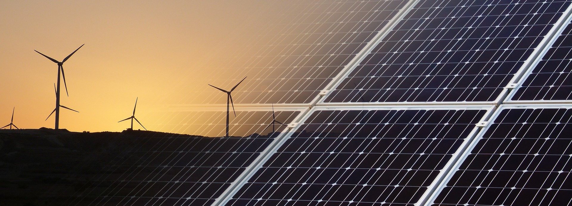 Solarkollektoren eingeblendet im Vordergrund mit Windrädern vor einem Sonnenuntergang am Horizont