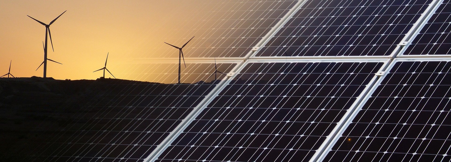 Solarkollektoren eingeblendet im Vordergrund mit Windrädern vor einem Sonnenuntergang am Horizont