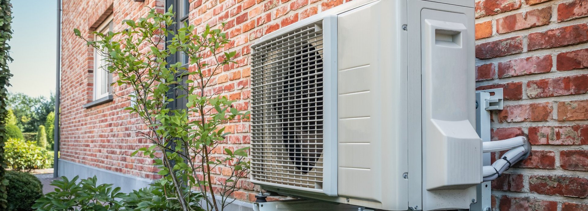 Beschreibung: Eine Wärmepumpe befindet sich an der Außenwand eines Wohnhauses