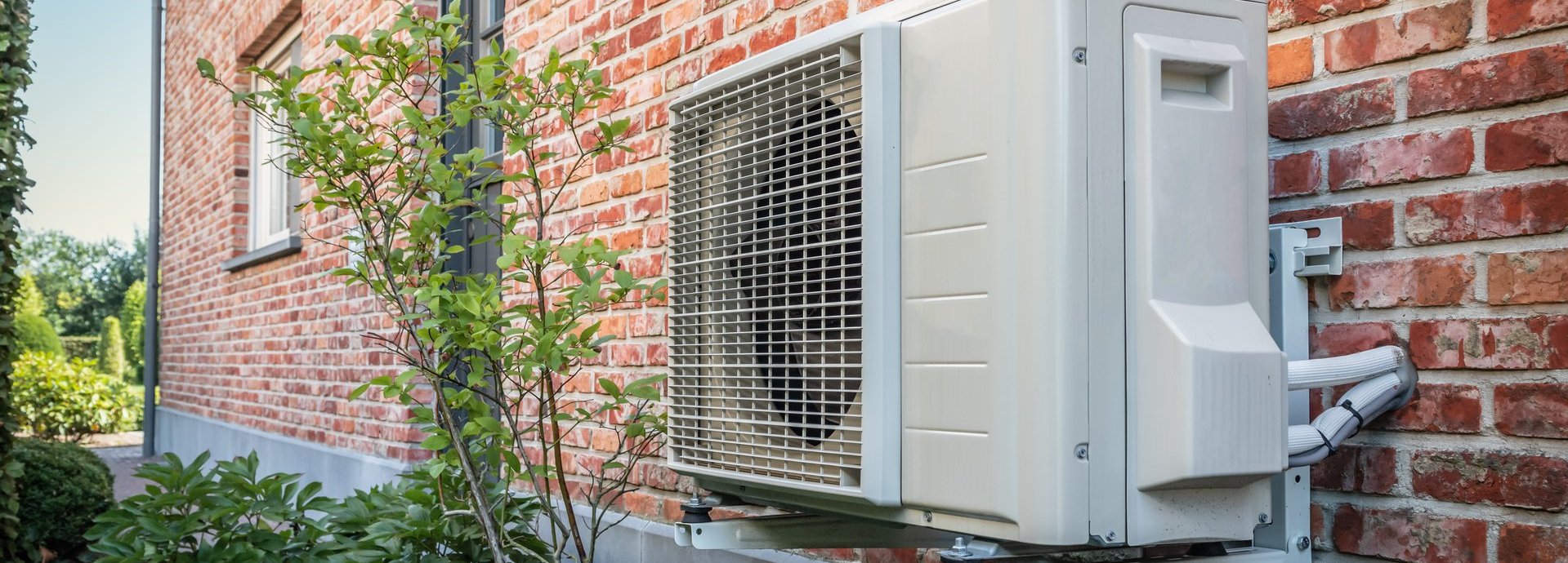 Beschreibung: Eine Wärmepumpe befindet sich an der Außenwand eines Wohnhauses