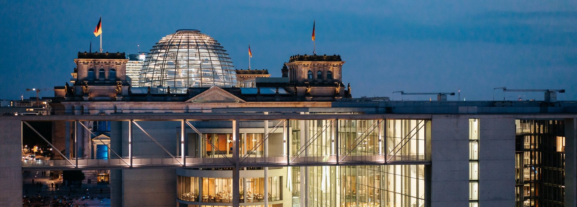 Glaskuppel des Bundestagi bei Nacht, beleuchtet und in der Ferne