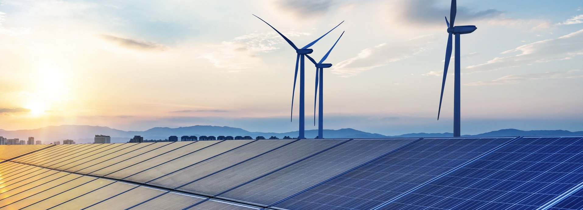 Beschreibung: Solarkollektoren mit Windrädern im Hintergrund vor blauem, wolkenbehangenem Himmel