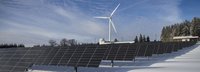 Solaranlagen und ein Windrad im Hintergrund im Winter auf schneebedecktem Feld