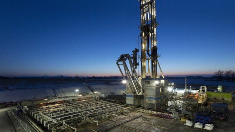Beleuchteter Geothermie Bohrturm vor einem dunkelblauen Himmel