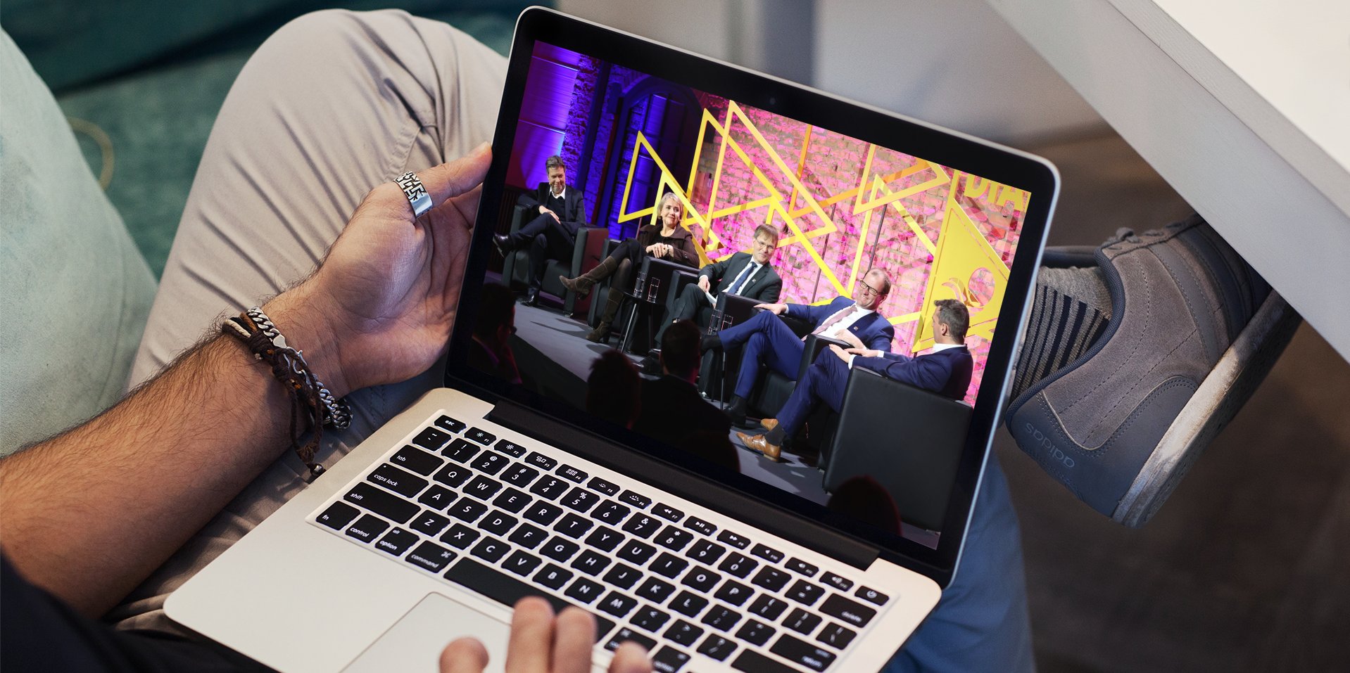Mann hält Macbook auf seinem Schoß, von dem aus er am Energiedialog teilnimmt