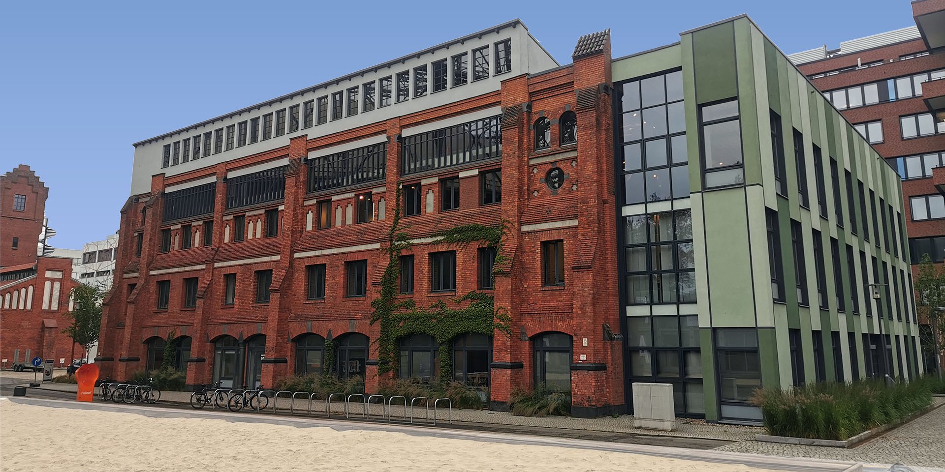 Haus 16 auf dem EUREF-Campus, Ziegelsteingebäude mit Volleyballfeld im Vordergrund