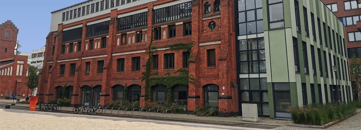 Haus 16 auf dem EUREF-Campus, Ziegelsteingebäude mit Volleyballfeld im Vordergrund