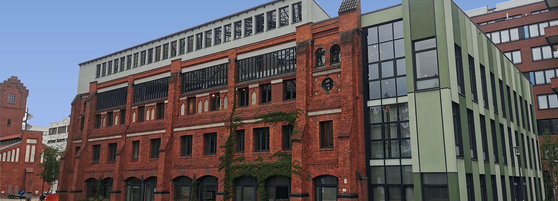 Beschreibung: Haus 16 auf dem EUREF-Campus, Ziegelsteingebäude mit Volleyballfeld im Vordergrund