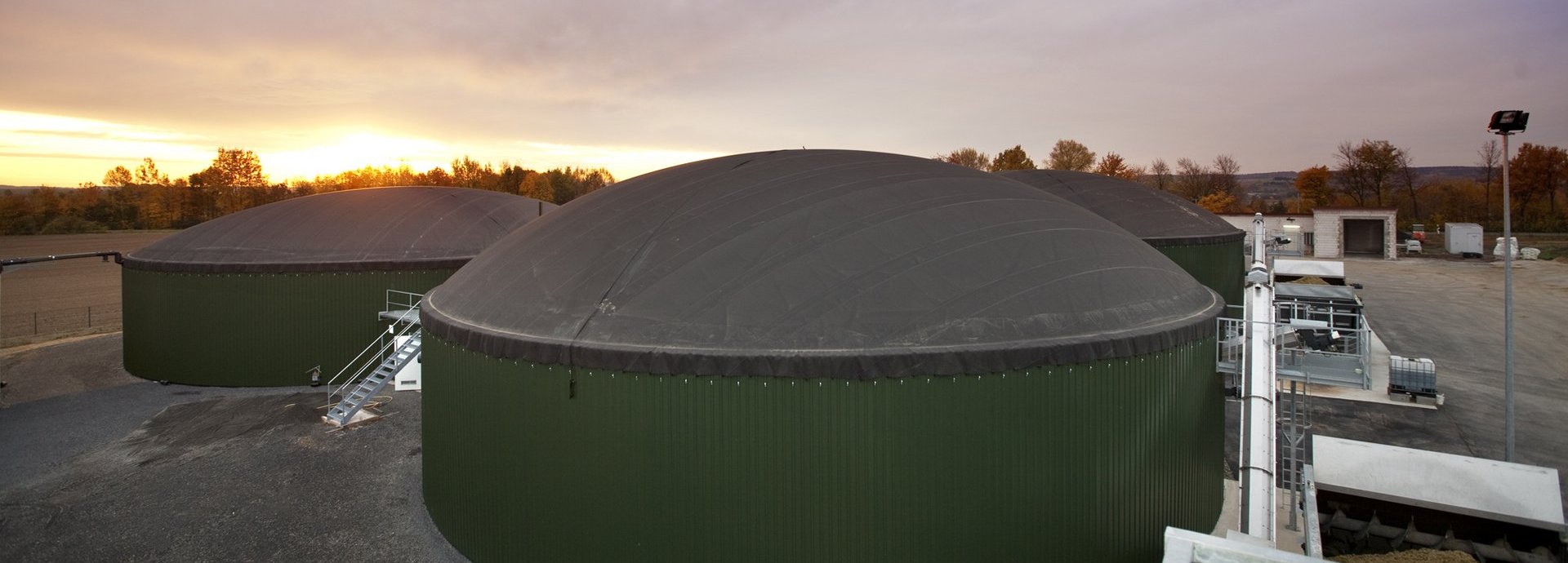 Biogasanlage Wollbrandshausen vor bewölktem Himmel und Sonnenuntergang