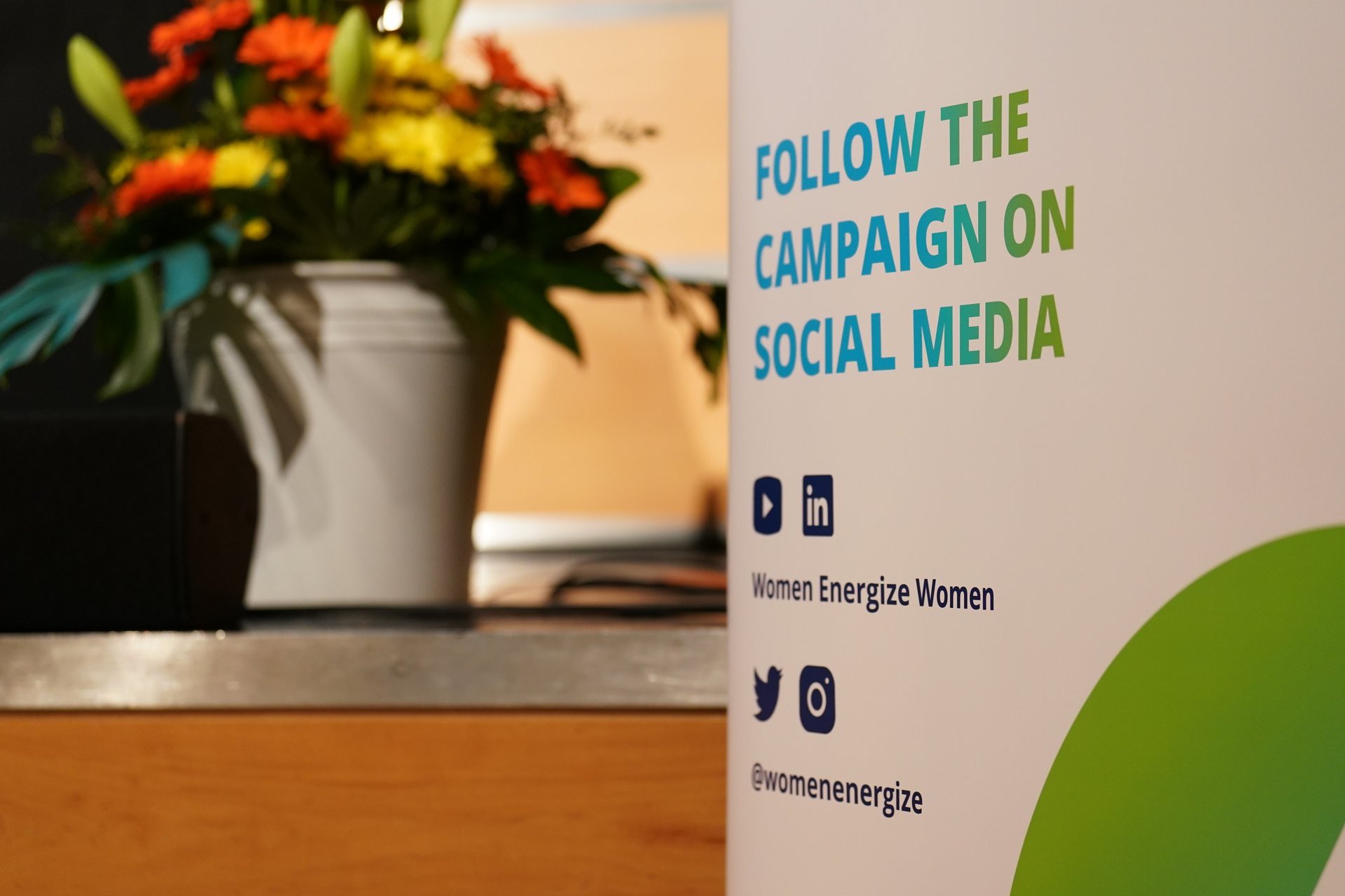 Plakat mit Hinweis der Social Media Kanäle der Women Energize Women Kampagne