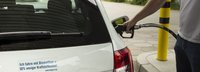 ich fahre mit Biomethan 50 prozent weniger kraftstoff Zeichen an einem weißen Auto das gerade geladen wird