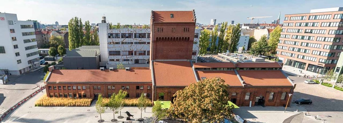 EUREF-Platz auf dem EUREF Campus ziegelfarbenes Gebäude mit offenem Hof aus Asphalt