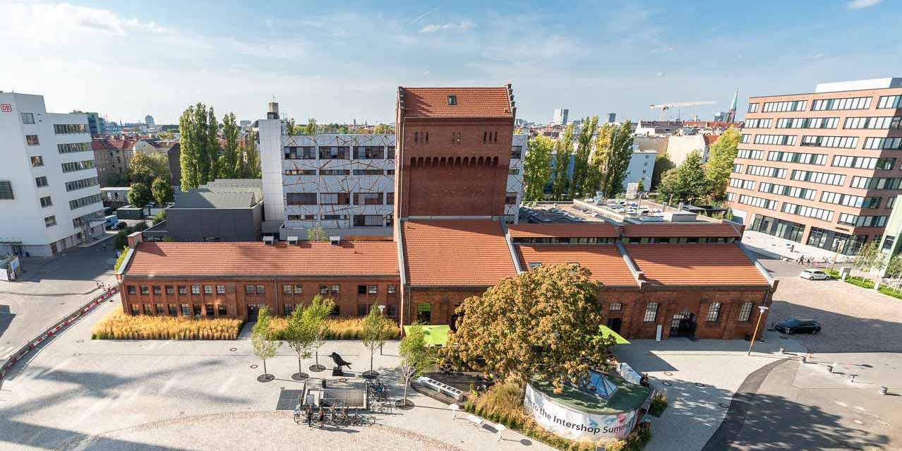 EUREF-Platz auf dem EUREF Campus ziegelfarbenes Gebäude mit offenem Hof aus Asphalt