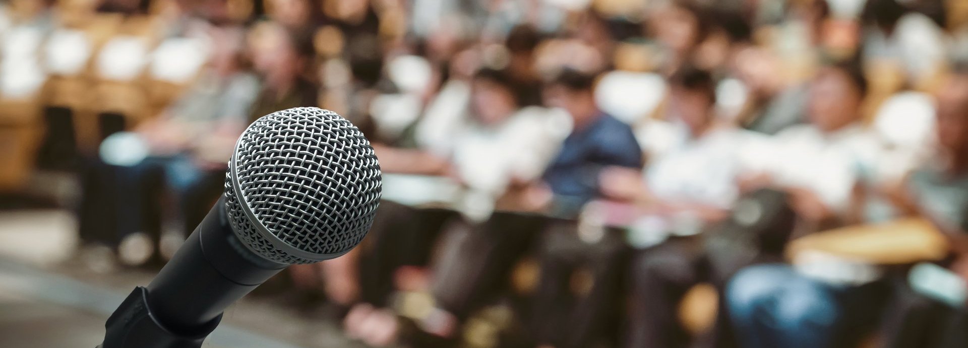 Mikrofon über dem Abstraktes unscharfes Foto des Konferenzsaals oder Seminarraums mit Teilnehmerhintergrund
