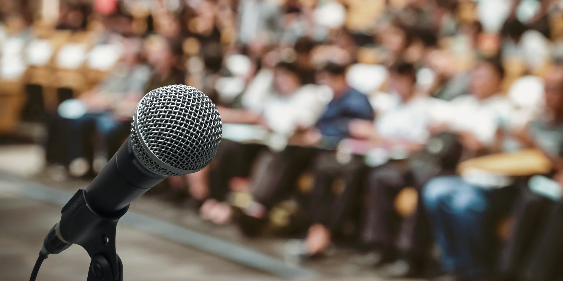 Mikrofon über dem Abstraktes unscharfes Foto des Konferenzsaals oder Seminarraums mit Teilnehmerhintergrund