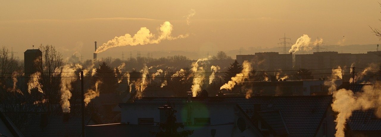 Beschreibung: Häuser mit rauchenden Schornsteinen von der Sonne angestrahlt